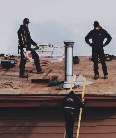 Roofing crew working on roof cleanup and debris handling